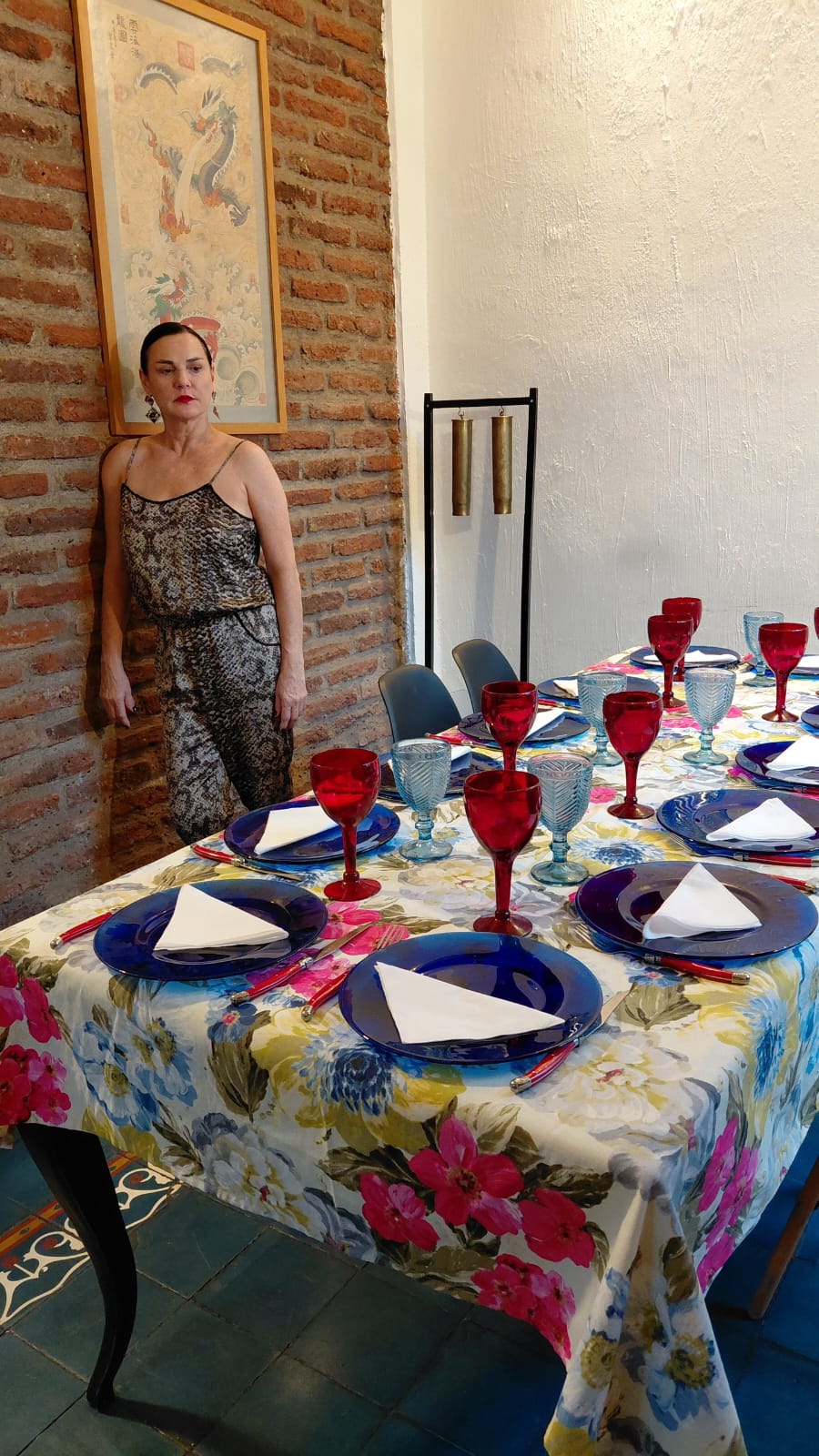 Berta Lasala junto a una mesa preparada con copas rojas y mantel floreado